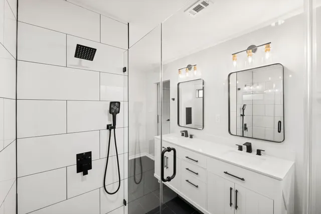 a bathroom with a double vanity sink mirror and shower