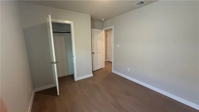 an empty room with wooden floor and closet area