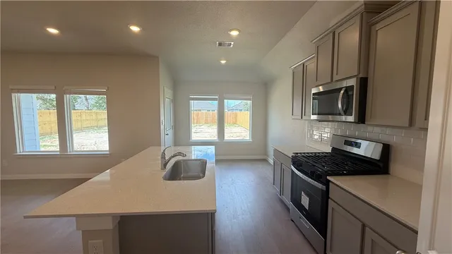 a kitchen with kitchen island granite countertop a sink appliances cabinets and a counter top space