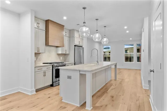 a large white kitchen with stainless steel appliances granite countertop a sink a stove and a refrigerator