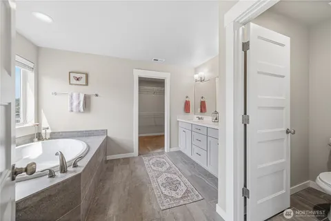 a spacious bathroom with a tub sink and mirror