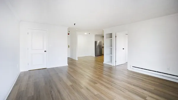 a view of an empty room with wooden floor