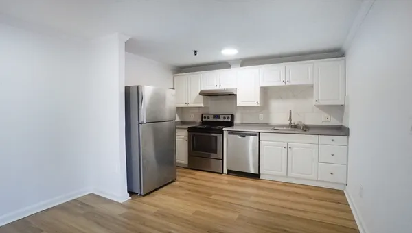 a kitchen with granite countertop a refrigerator stove and wooden floor