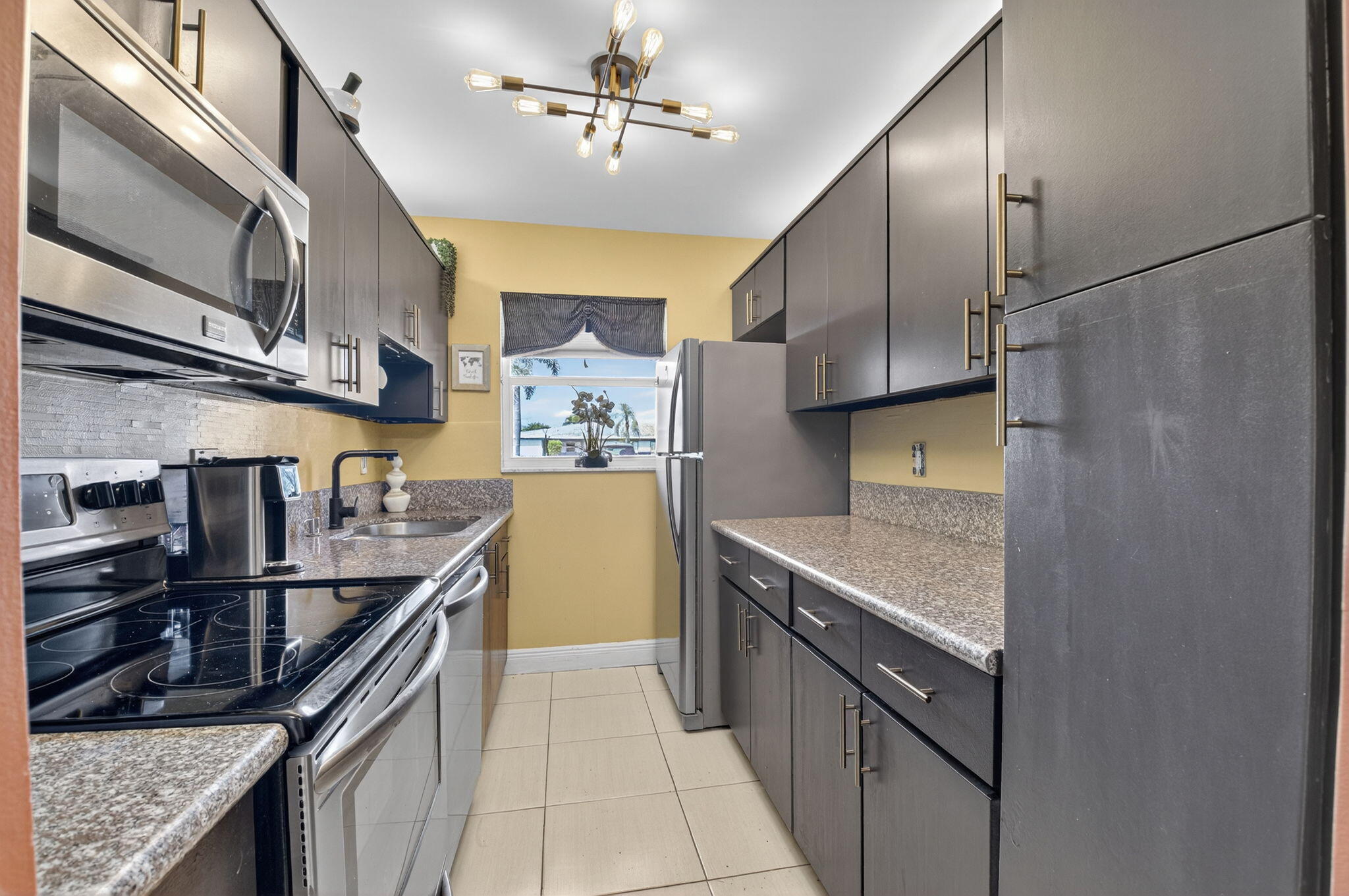 762 High Point Boulevard North, Unit D Delray Beach, FL 33445 - Photo 14 of 32 a kitchen with stainless steel appliances granite countertop a sink a stove and a refrigerator