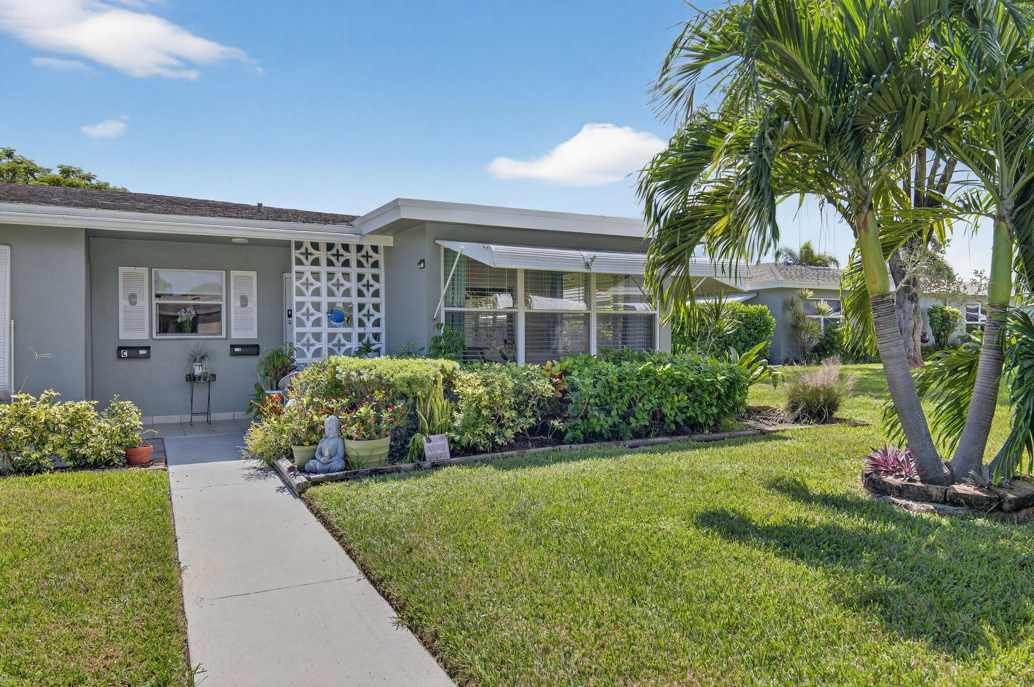 762 High Point Boulevard North, Unit D Delray Beach, FL 33445 - Photo 2 of 32 a front view of a house with a yard and potted plants