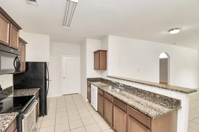 a kitchen with granite countertop a stove and a refrigerator