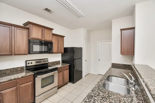 a kitchen with granite countertop a refrigerator stove and microwave