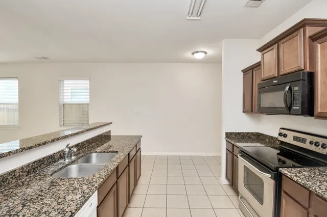 a kitchen with granite countertop a stove sink and cabinets
