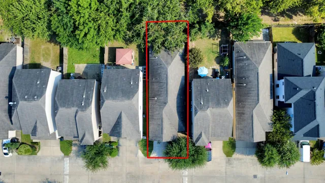 an aerial view of a house with a yard and a large tree