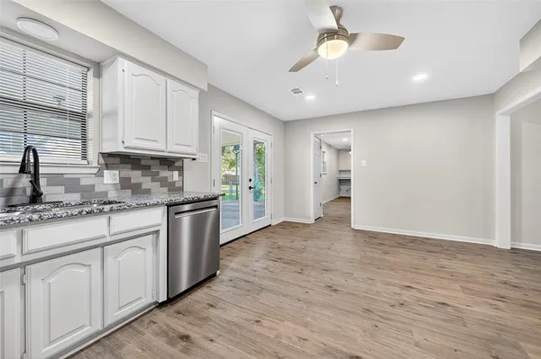 an empty room with wooden floor a ceiling fan and windows