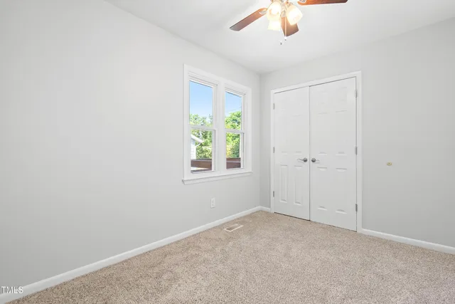 an empty room with a window and a fan