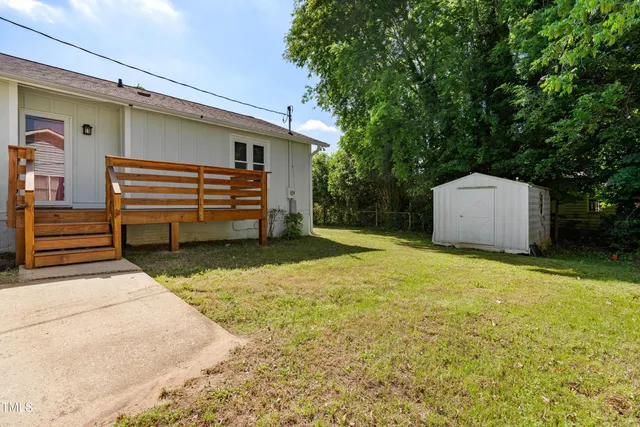 a backyard of a house with a large tree and wooden fence