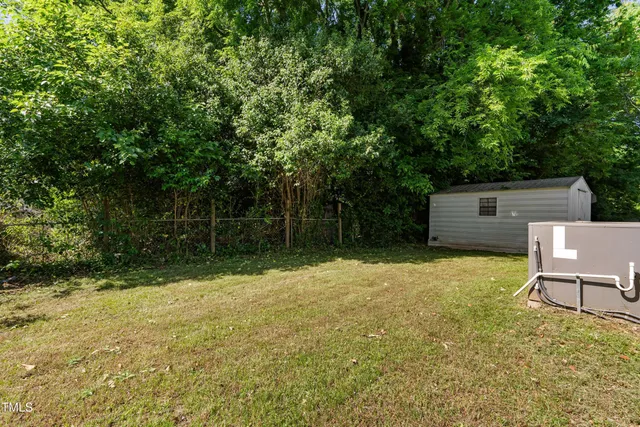a backyard of a house with yard plants and large tree