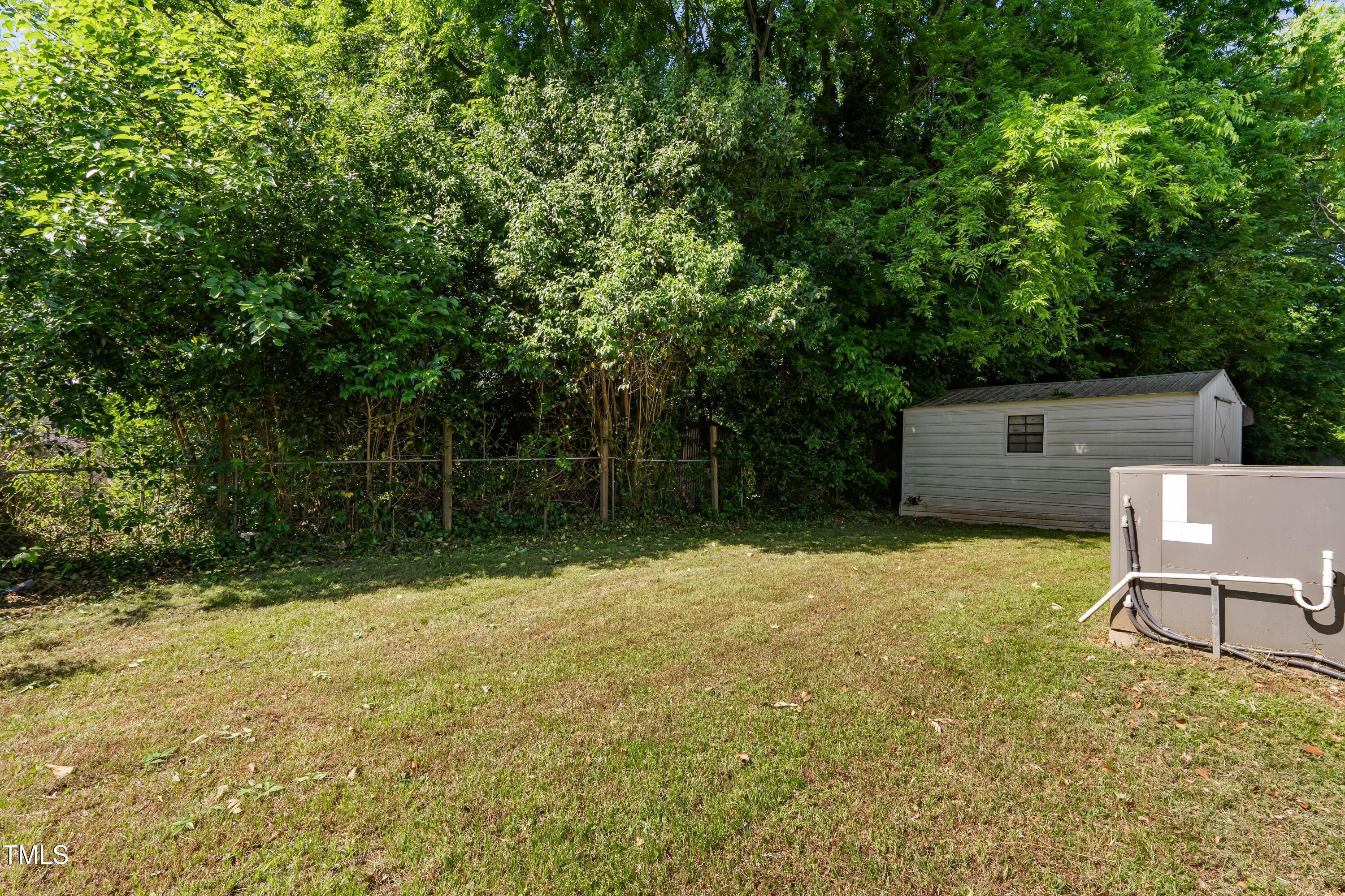 1212 Pender Street Raleigh, NC 27610 - Photo 17 of 19 a backyard of a house with yard plants and large tree