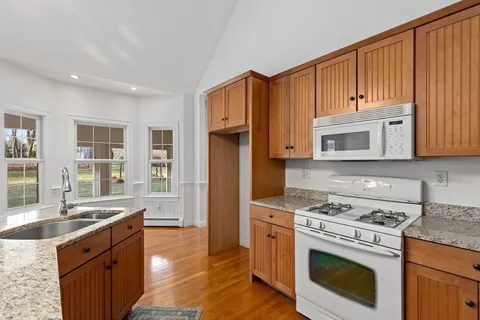 a kitchen with granite countertop a stove a sink dishwasher and a refrigerator with wooden cabinets