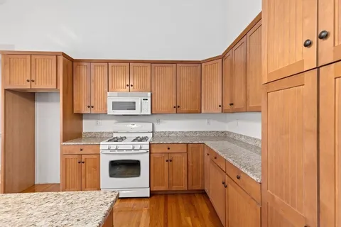 a kitchen with granite countertop wooden cabinets and white appliances