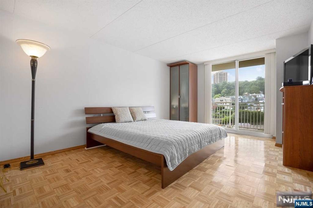1055 River Road, Unit 905 Edgewater, NJ 07020 - Photo 9 of 26 a spacious bedroom with a bed and a lamp next to a window