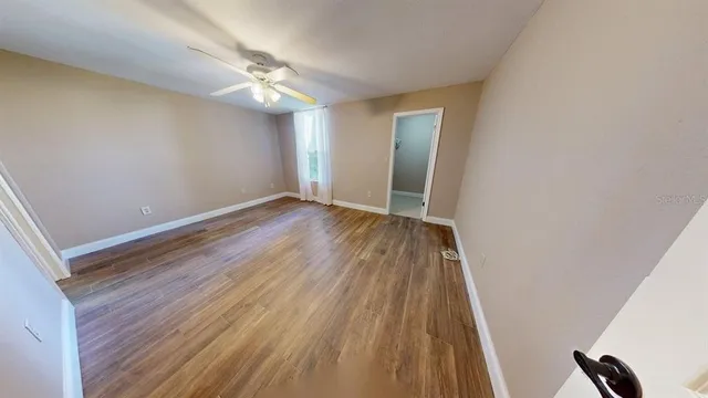 a view of an empty room with wooden floor and a window