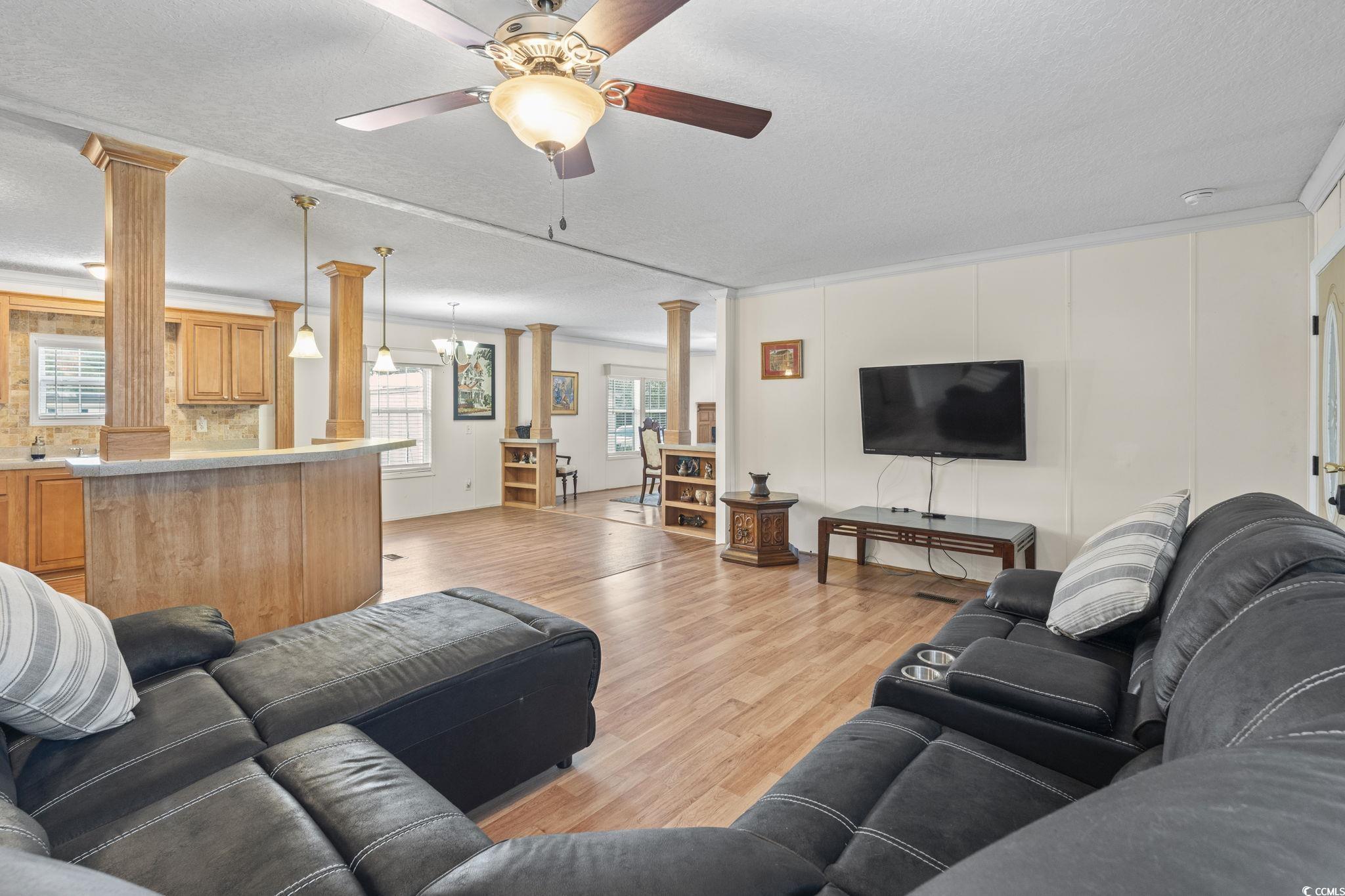 911 Old Magnolia Drive Conway, SC 29526 - Photo 12 of 35 Living area featuring ornate columns, crown molding, a textured ceiling, light wood-style flooring, and a ceiling fan