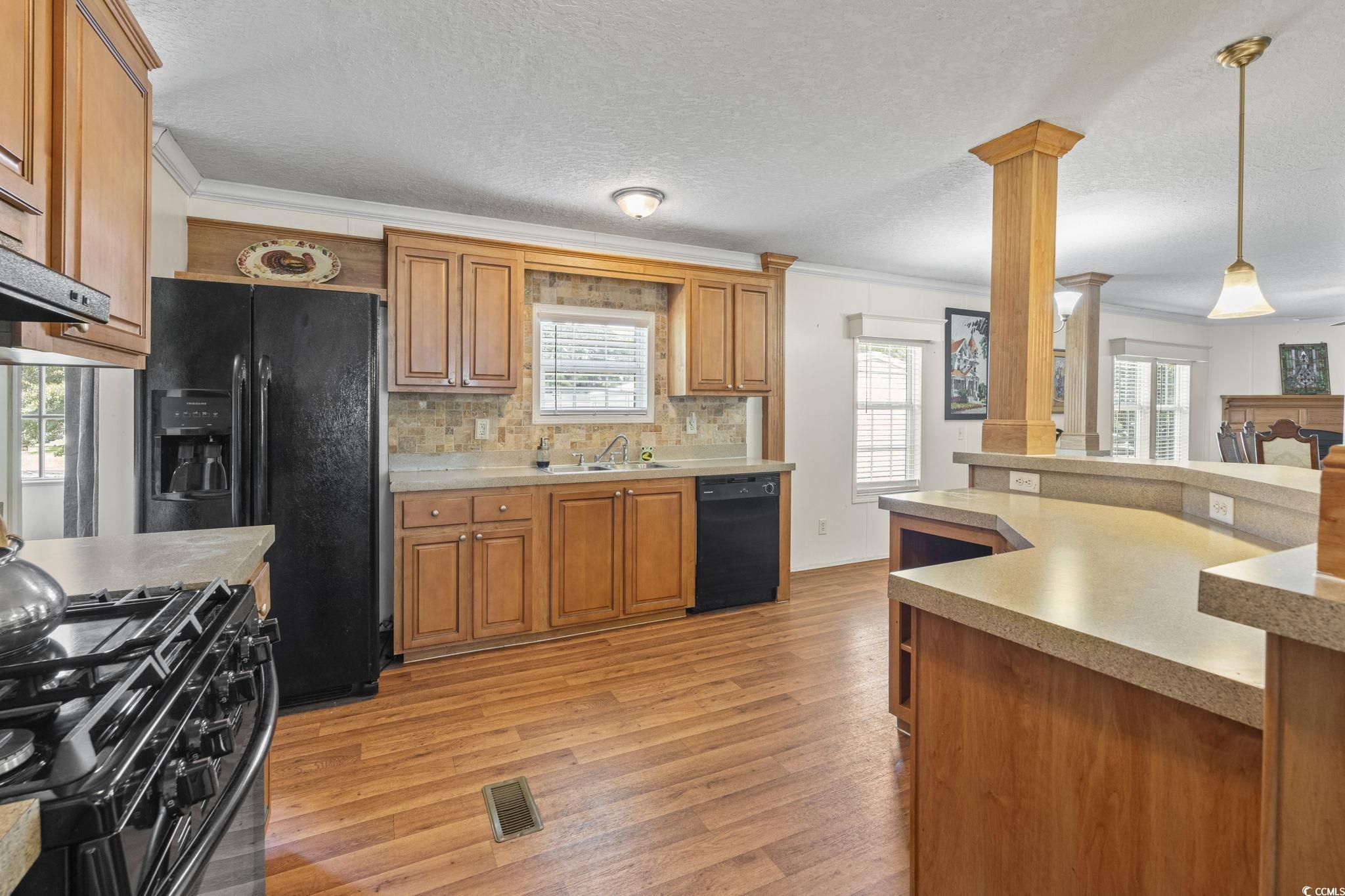 911 Old Magnolia Drive Conway, SC 29526 - Photo 15 of 35 Kitchen with ornamental molding, ornate columns, light wood-type flooring, black appliances, and hanging light fixtures