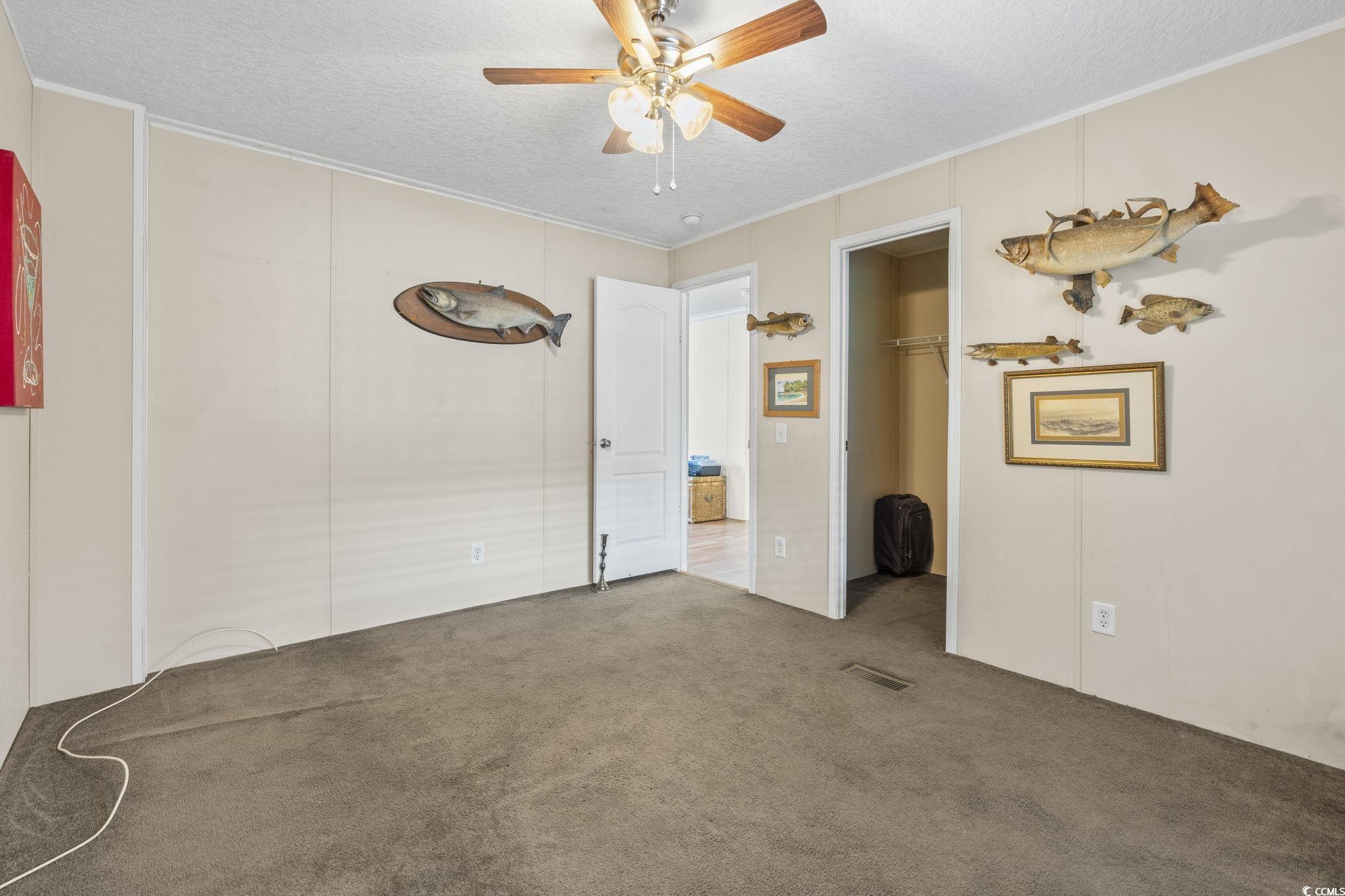 911 Old Magnolia Drive Conway, SC 29526 - Photo 28 of 35 Unfurnished bedroom featuring ornamental molding, carpet flooring, a textured ceiling, a walk in closet, and a ceiling fan