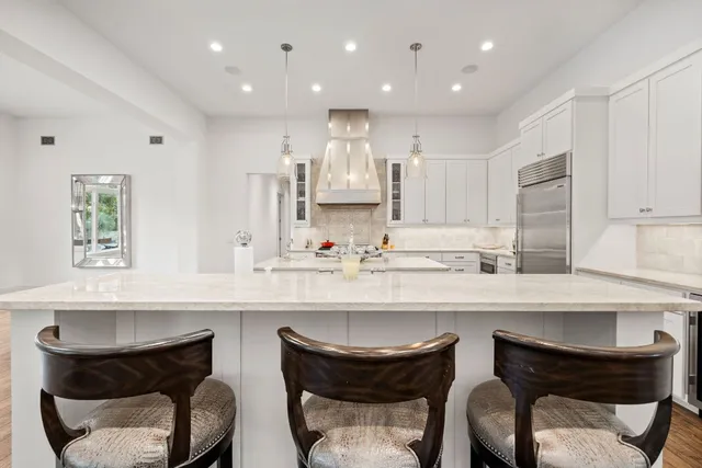 a kitchen with stainless steel appliances kitchen island granite countertop a stove a sink dishwasher and white cabinets with wooden floor