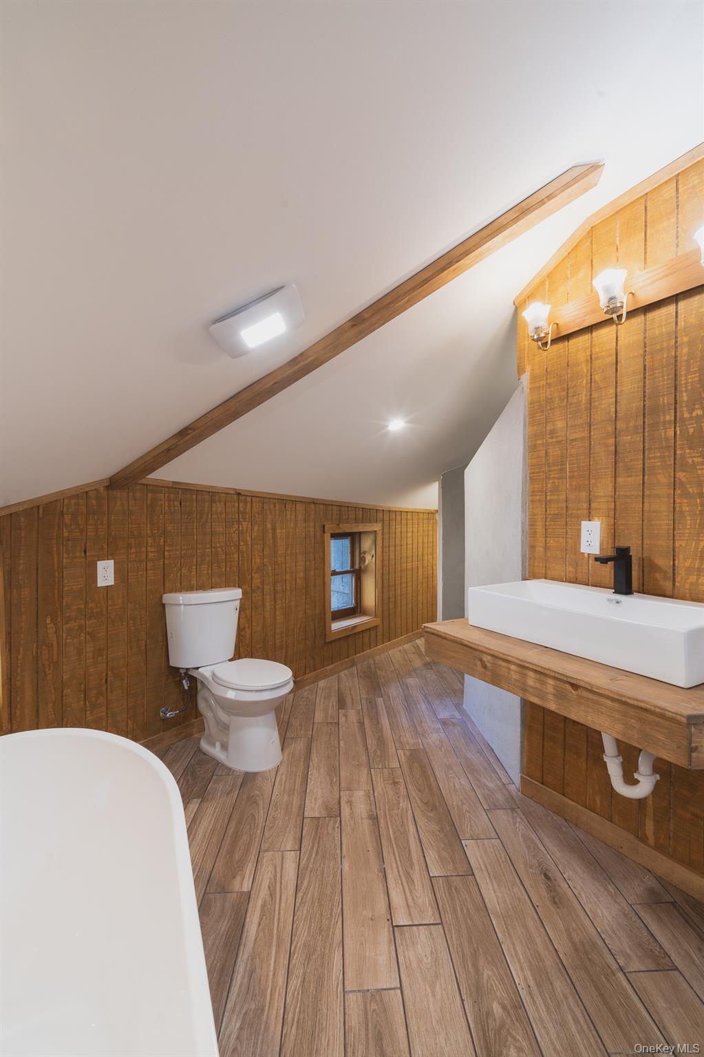 15 Deans Road Napanoch, NY 12458 - Photo 8 of 21 Bathroom featuring wood walls, wood finished floors, a freestanding bath, and vanity