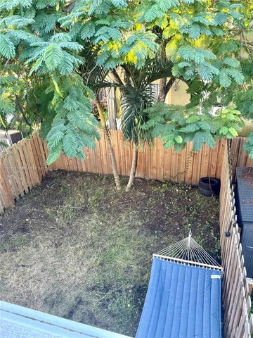a view of a backyard with large trees and wooden fence