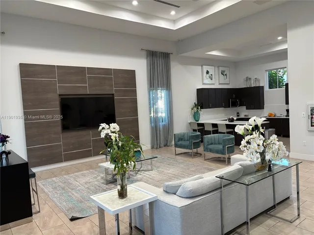 a living room with furniture a potted plant and a kitchen view