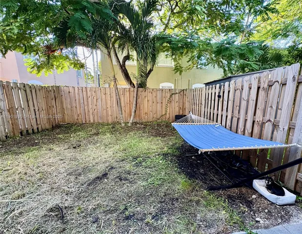 a view of a backyard with a wooden fence and a large tree