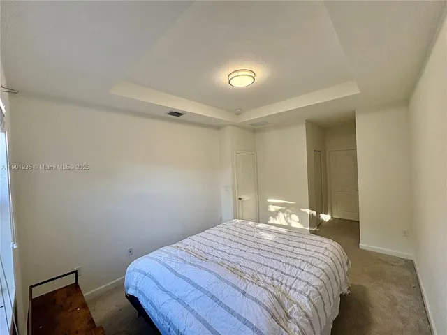 a bedroom with a bed and a lamp on the dresser