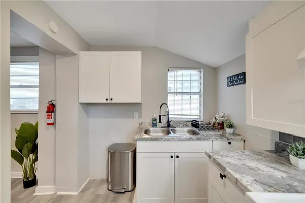 a kitchen with granite countertop a sink a window and cabinets