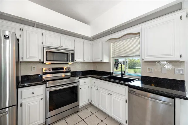 a kitchen with white cabinets and appliances