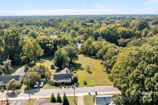 an aerial view of residential houses with outdoor space and trees