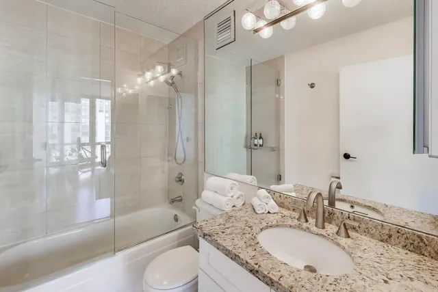 a bathroom with a granite countertop sink toilet and shower