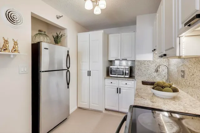 a kitchen with stainless steel appliances granite countertop a refrigerator a stove a sink and dishwasher with wooden floor