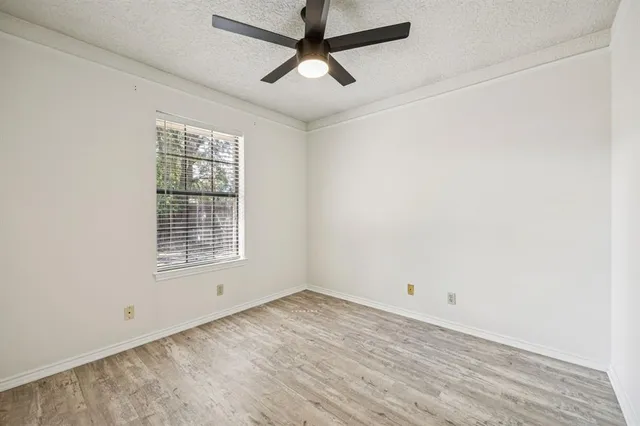an empty room with a window and a ceiling fan