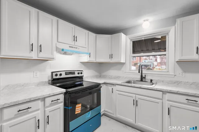 a kitchen with granite countertop white cabinets and white appliances