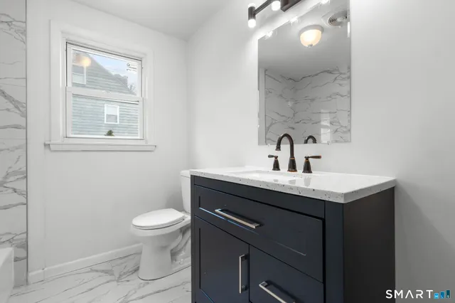 a bathroom with a toilet a sink and mirror