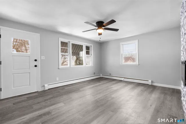 a view of an empty room with wooden floor and a window