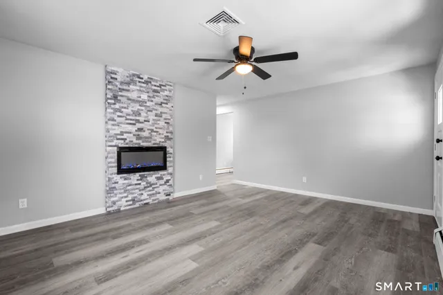 a view of an empty room with window and wooden floor