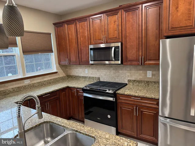 a kitchen with granite countertop wooden cabinets and a stove top oven