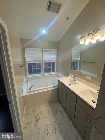 a bathroom with a tub sink and mirror