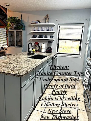 a kitchen with granite countertop a stove and a white cabinets