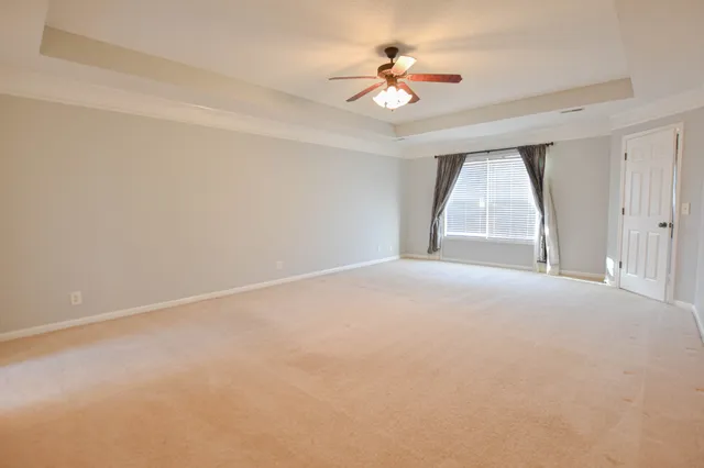 an empty room with windows and ceiling fan