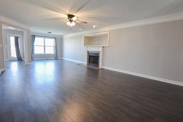 a view of an empty room with wooden floor fireplace and a window