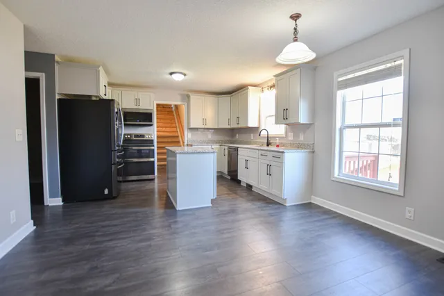 a kitchen with stainless steel appliances a stove refrigerator and wooden floor