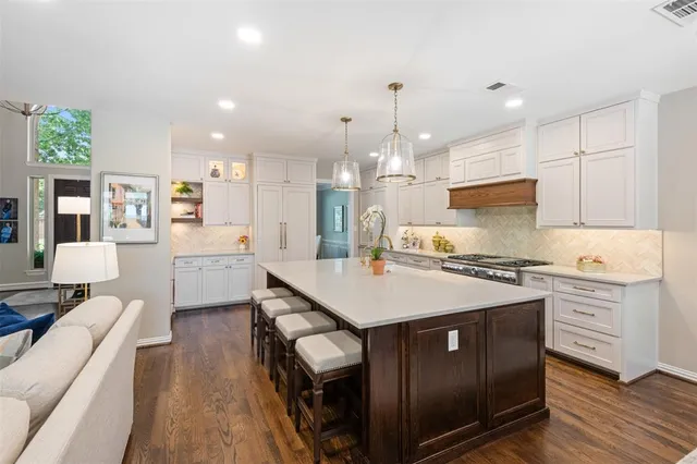 a large kitchen with stainless steel appliances kitchen island a stove a sink dishwasher and a refrigerator with wooden floor