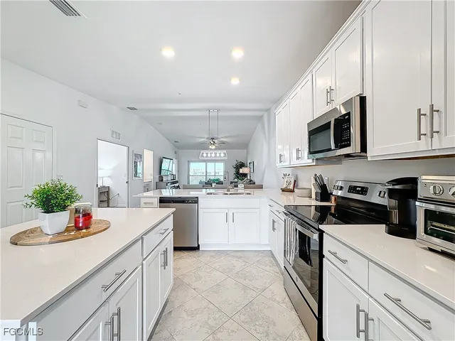 a kitchen with granite countertop a sink stainless steel appliances and white cabinets