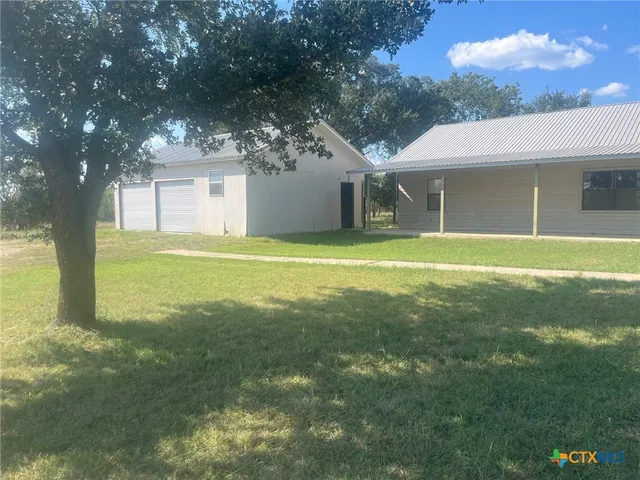 a view of a big yard next to a house with large trees